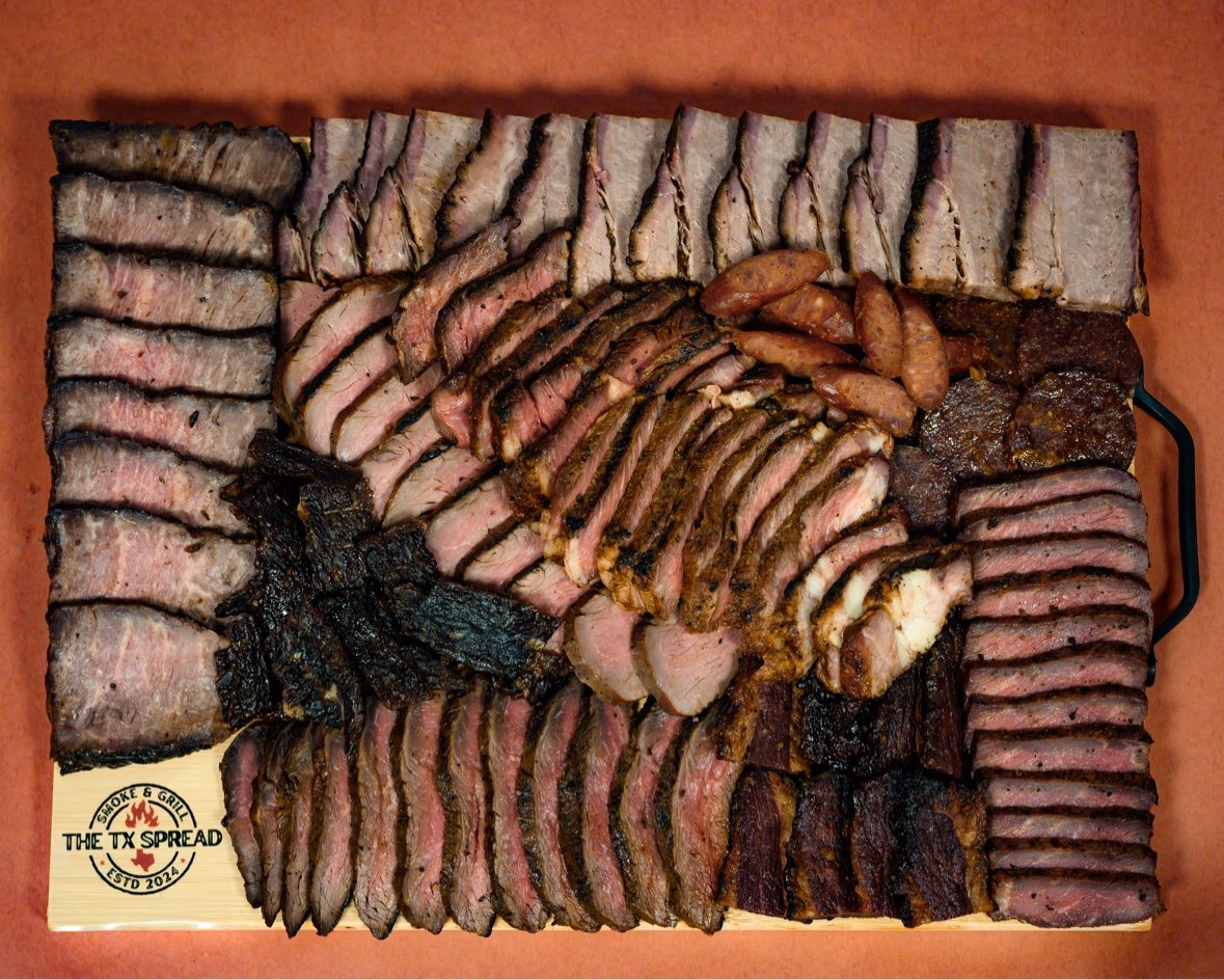 Overhead view of a full Tx Spread board covered edge to edge with sliced smoked meats